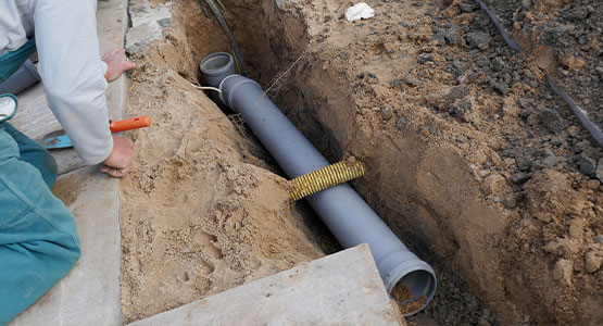Person installing drainage pipe in a trench.