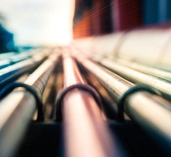 Close-up of industrial pipes with sunlight in the background.