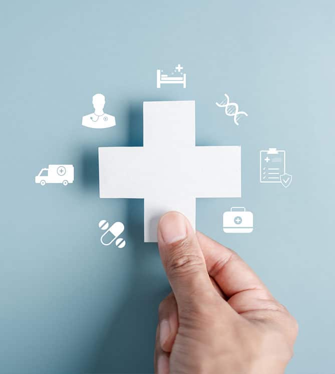 Hand holding white cross symbol surrounded by medical icons on blue background.